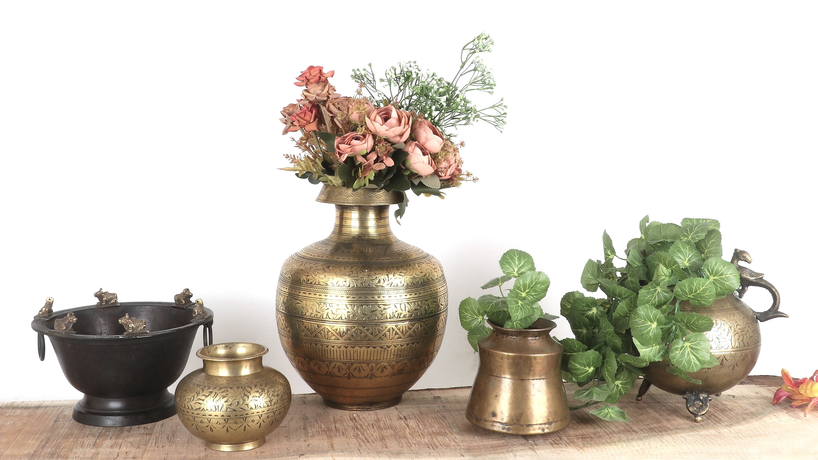 Collection of decorative vases and pots with plants on a wooden surface