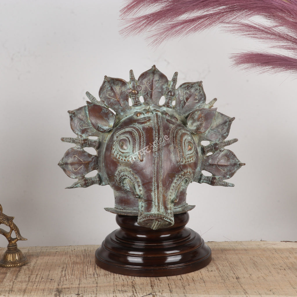 Bronze mask on a wooden base with a feather in the background