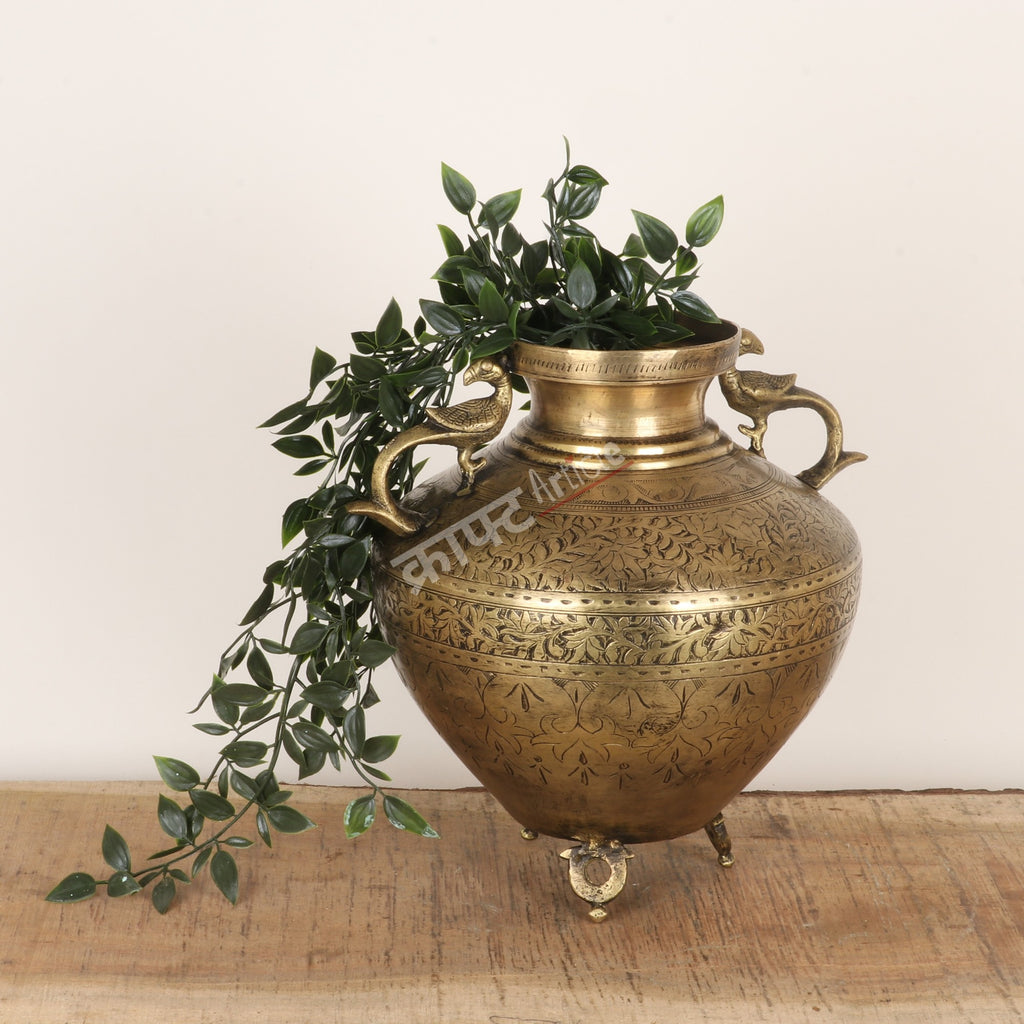 Decorative brass vase with plant on a wooden surface